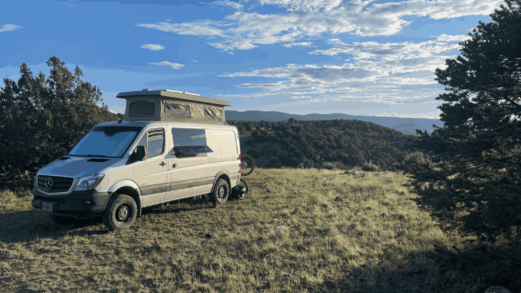 Sprinter van with pop up camper parked on grassy orverlook